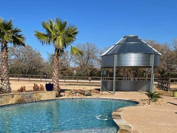 metal structure made from grain mill next to pool and palm trees